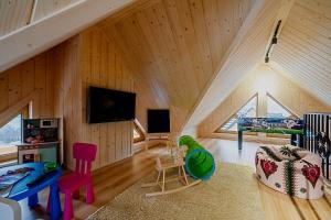 a attic room with a wooden ceiling and a room with a couch at Eco dom z sauną- Pasja II View,Lake & Ski in Kluszkowce