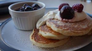 a plate with two pancakes with berries and whipped cream at Bluebird Lodge in Coniston