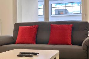 Sofá gris con 2 almohadas rojas y mesa de centro en Ladybug Terace #AV, en Meylan