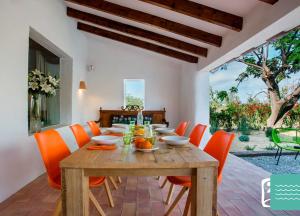 une salle à manger avec une table en bois et des chaises orange dans l'établissement VILLA TOSCANA, à Benissa