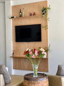 a vase with flowers on a table in front of a tv at Hotel Somensi in Bento Gonçalves