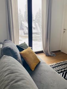 a couch with two pillows sitting in front of a window at Apartman Maris in Šišava