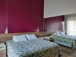 ein Hotelzimmer mit zwei Betten und lila Wänden in der Unterkunft Flat Particular Adeias das Aguas Park Resort in Barra do Piraí + 37 Fotos