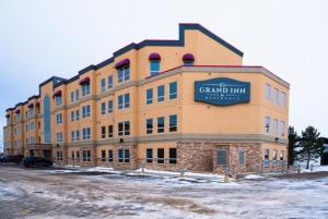 a large building with a sign on the front of it at Grand Inn & Residence- Grande Prairie in Grande Prairie