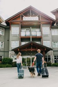 a man and a woman walking a dog in front of a building at Old House Hotel & Spa in Courtenay