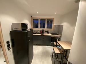 a small kitchen with a black refrigerator and a table at Chambre privée in Villiers-en-Bière