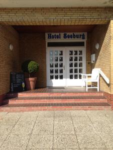 ein Gebäude mit einer Tür und einer Bank vorne in der Unterkunft Hotel Seeburg in Sankt Peter-Ording