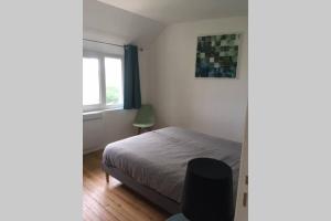 1 dormitorio con cama, ventana y silla en Maison bord de Mer en Bernières-sur-Mer