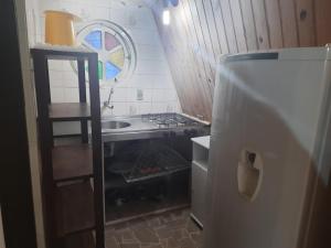 a small kitchen with a stove and a refrigerator at Chalés Monções in Ubatuba