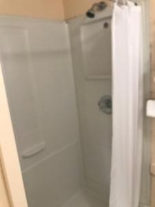 La salle de bains est pourvue d'une douche avec rideau de douche blanc. dans l'établissement Riverview Inn, à Grayling