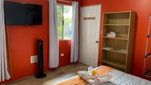 a bedroom with orange walls and a bed with a flat screen tv at Hotel Your House in Alajuela