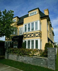 ein gelbes Haus mit einem Zaun davor in der Unterkunft The Beacon Inn at Sidney in Sidney