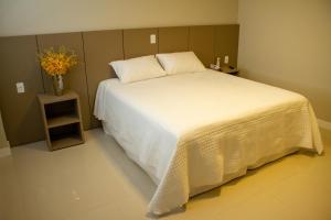 een slaapkamer met een groot bed en een vaas met bloemen bij Hotel Seville Comfort in Telêmaco Borba