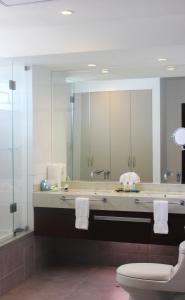 VPX Hotel في آسيا: حمام مع مرآة كبيرة ومرحاض