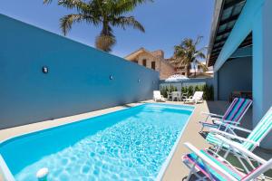 a swimming pool with chairs and a blue building at Casa Patta - 05 dormitórios, com piscina. in Bombinhas