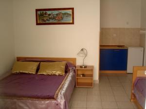 a bedroom with a bed with purple sheets and a lamp at Apartments Odalović in Bijela