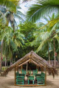 a gazebo with green chairs and palm trees at Playa 506 Beachfront Hostel in Puerto Viejo