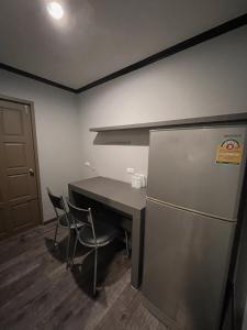a kitchen with a refrigerator and a table with chairs at Carpediem Hotel in Rayong