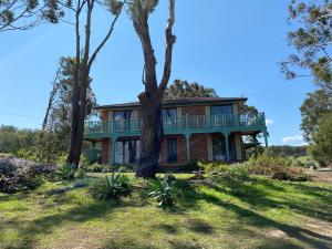 una casa en una colina con árboles en primer plano en Hunter Homestead, Lovedale, en Rothbury