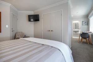 a bedroom with a bed and a tv on the wall at Ambience on Pacific B&B in Palmerston North