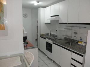 a small kitchen with white cabinets and a sink at NA BEIRA MAR DE PAJUCARA- EDIF NEO- APARTAMENTO QUARTO E SALA - TEM VARANDA - VISTA LATERAL DO MAR - RUA JULIO PLECH FILHO 60 ESQUINA COM AVENIDA DOUTOR ANTONIO GOUVEIA - CONSUMO ELETRICO É PAGO No CKECK-OUT 1KWH É 1,35 REIAS - ANDAR "6" in Maceió