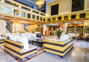 a lobby with couches and tables in a building at Tohsang Heritage Ubon Ratchathani Hotel in Ubon Ratchathani