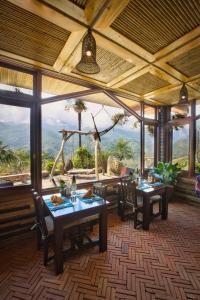 a dining room with tables and chairs and a large window at Eco Palms House - Sapa Retreat in Sa Pa