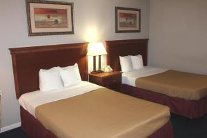 una habitación de hotel con 2 camas y una lámpara en Interstate Motel, en Rensselaer