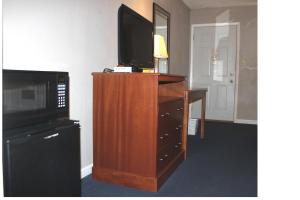a television on top of a wooden dresser with a desk at Interstate Motel in Rensselaer