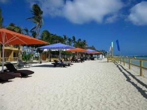 a beach with chairs and umbrellas on the beach at Marlins Beach Resort in Bantayan Island