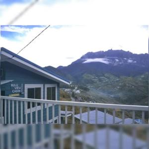 a balcony of a house with a snow covered mountain at Nulu View Cabin in Kundasang