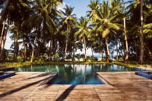 a swimming pool with palm trees and a boardwalk at Sea Shell Resort & Spa, Havelock in Havelock Island