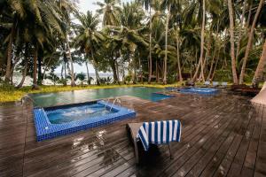 a swimming pool with two chairs on a wooden deck at Sea Shell Resort & Spa, Havelock in Havelock Island