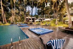 a swimming pool with two chairs and a wooden deck at Sea Shell Resort & Spa, Havelock in Havelock Island