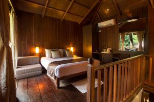 a bedroom with a bed and a chair in a room at Sea Shell Resort & Spa, Havelock in Havelock Island