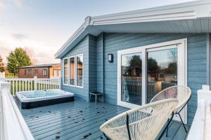 a blue house with a hot tub on a deck at The Haven Lodge with Hot Tub in York