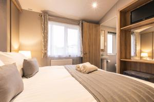 1 dormitorio con 1 cama blanca grande y ventana en The Haven Lodge with Hot Tub en York