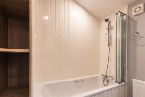 a white bath tub in a bathroom with a shower at The Haven Lodge with Hot Tub in York +16 photos