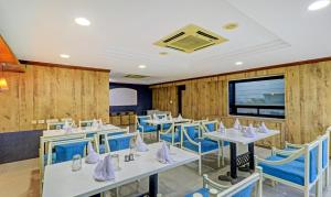 un restaurante con mesas blancas y sillas azules en Treebo Trend Orange City, en Nagpur