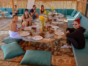 a group of people sitting around a table at Bedouin Oasis Desert Camp- Ras Al Khaimah in Ras al Khaimah