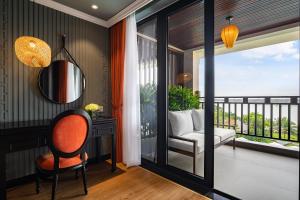 Cette chambre dispose d'un balcon, d'un miroir et d'une chaise. dans l'établissement Bel Marina Hoi An Resort, à Hội An