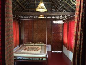 een bed in een kamer met rode gordijnen bij Cherai Beach Retreat in Cherai Beach