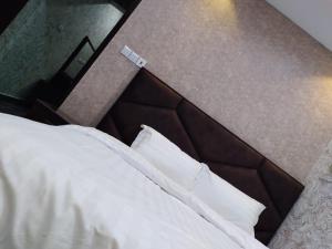 1 dormitorio con 1 cama con sábanas y almohadas blancas en Iwaa Alkharj Apartments, en Al Kharj