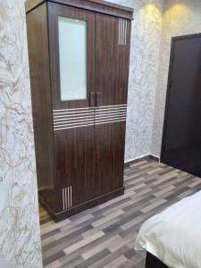 1 dormitorio con un gran armario de madera con puerta en Iwaa Alkharj Apartments, en Al Kharj
