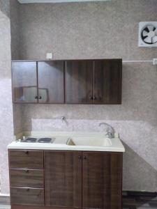 a kitchen with a sink and wooden cabinets at Iwaa Alkharj Apartments in Al Kharj