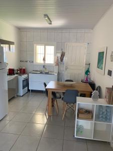 a kitchen with a wooden table and a kitchen with white appliances at Casa Aconchego e Sossego Imbé in Imbé