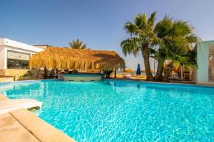 uma grande piscina com um guarda-sol de palha e palmeiras em The Boutique Hotel Hurghada Marina em Hurghada