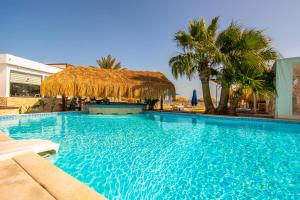 a large swimming pool with a straw umbrella and palm trees at The Boutique Hotel Hurghada Marina in Hurghada