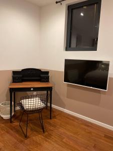 um quarto com uma mesa, uma televisão e uma cadeira em L'Atelier des Magnolias em Aumont
