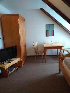 Zimmer mit einem Tisch, einem TV, einem Tisch und einem Stuhl in der Unterkunft Pension Töpferhof in Bad Berka